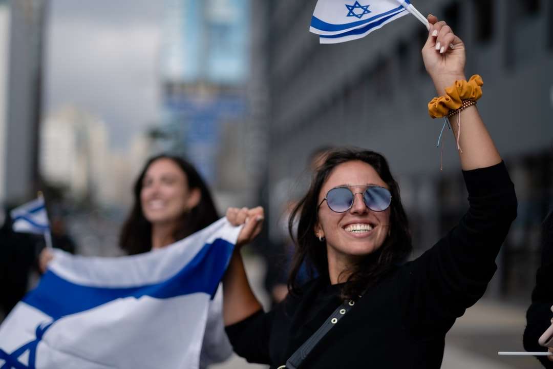 жена в черна риза с дълъг ръкав, държаща бяло и синьо знаме онлайн пъзел