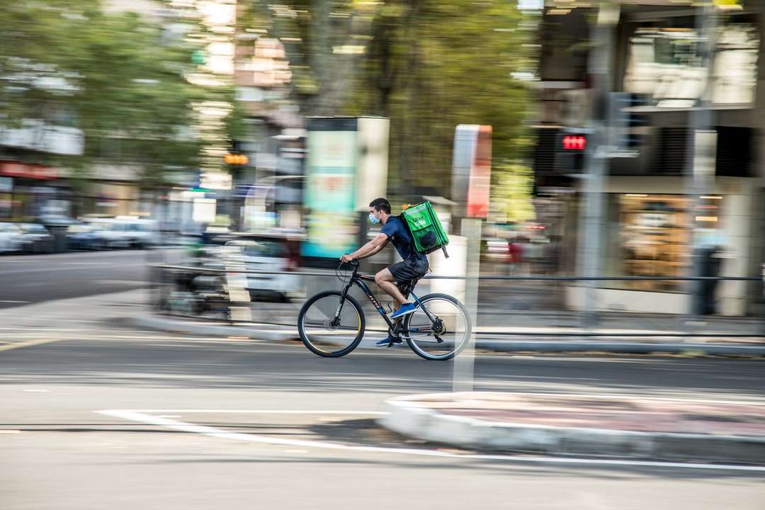 homem de camisa verde andando de bicicleta na estrada durante o dia puzzle online