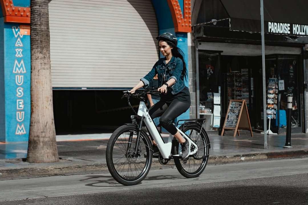 Frau in der blauen Denimjacke, die auf schwarzem Fahrrad reitet Puzzlespiel online