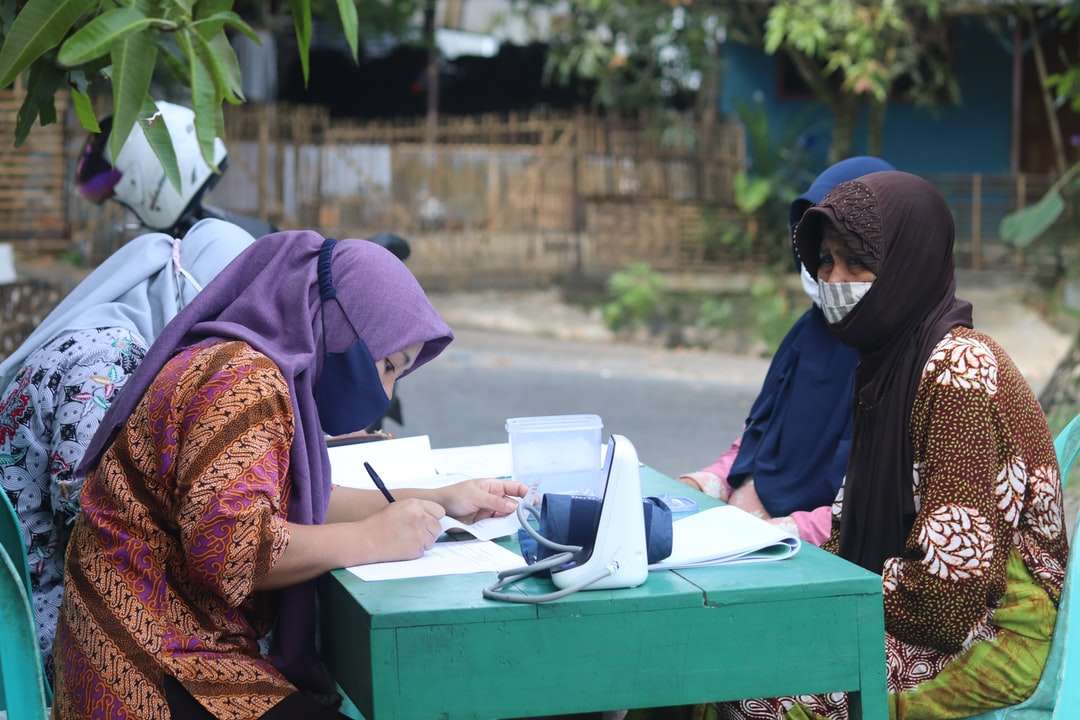 Frau in braunem und rotem Hijab sitzt auf grüner Kiste Online-Puzzle