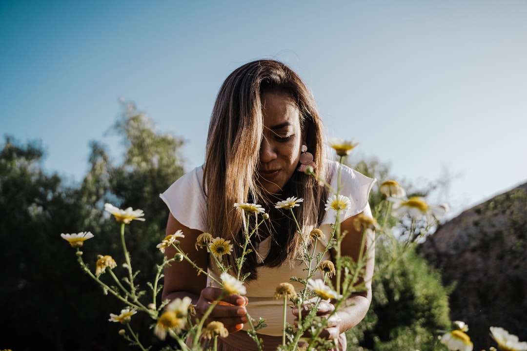 Frau im weißen Hemd, das weiße Blumen hält Puzzlespiel online