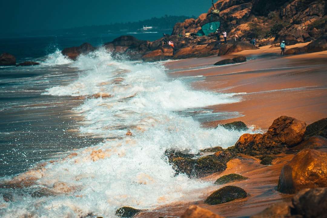 Vlny oceánu narazili na hnědé skalní útvar během dne skládačky online
