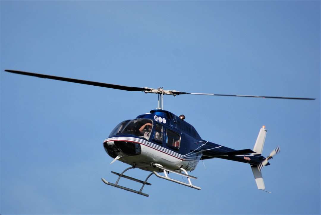 Blå och vit helikopter som flyger i himlen under dagtid Pussel online