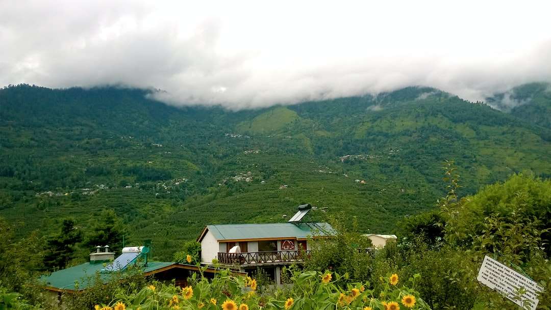 Πράσινο και λευκό σπίτι σε πράσινο βουνό κάτω από λευκά σύννεφα online παζλ