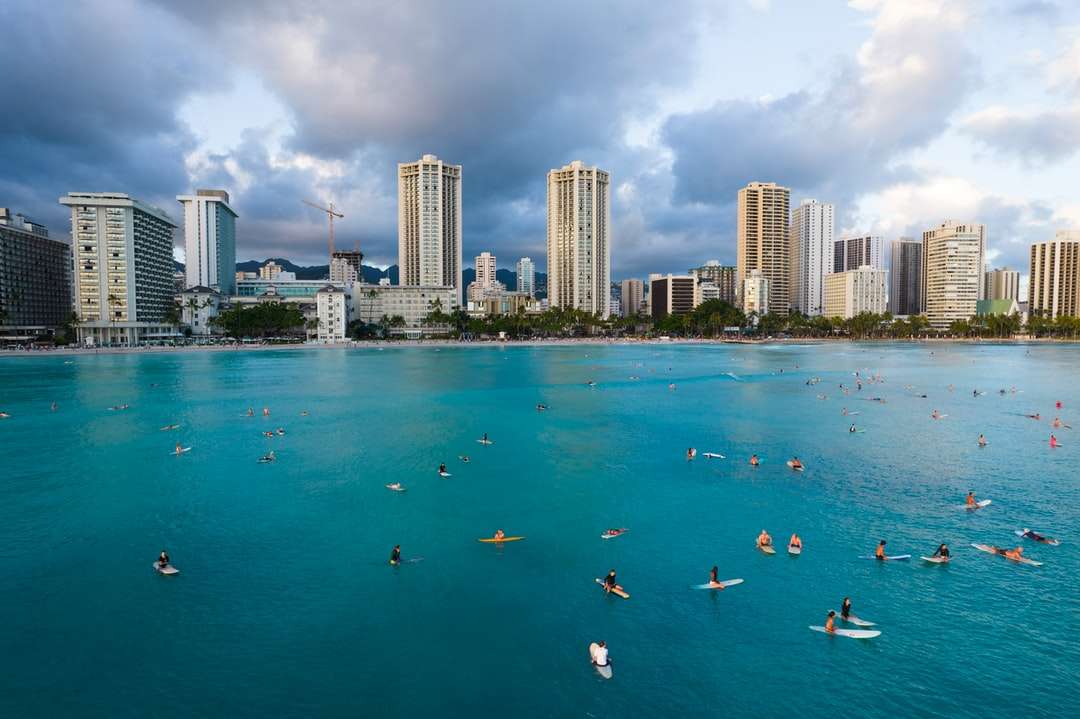 Хората плуват на плажа близо до високи сгради онлайн пъзел
