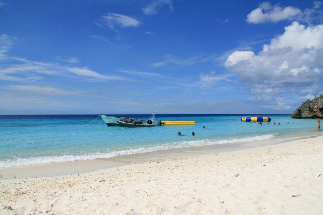 Fehér és kék csónak a tengerparton nappali parton online puzzle