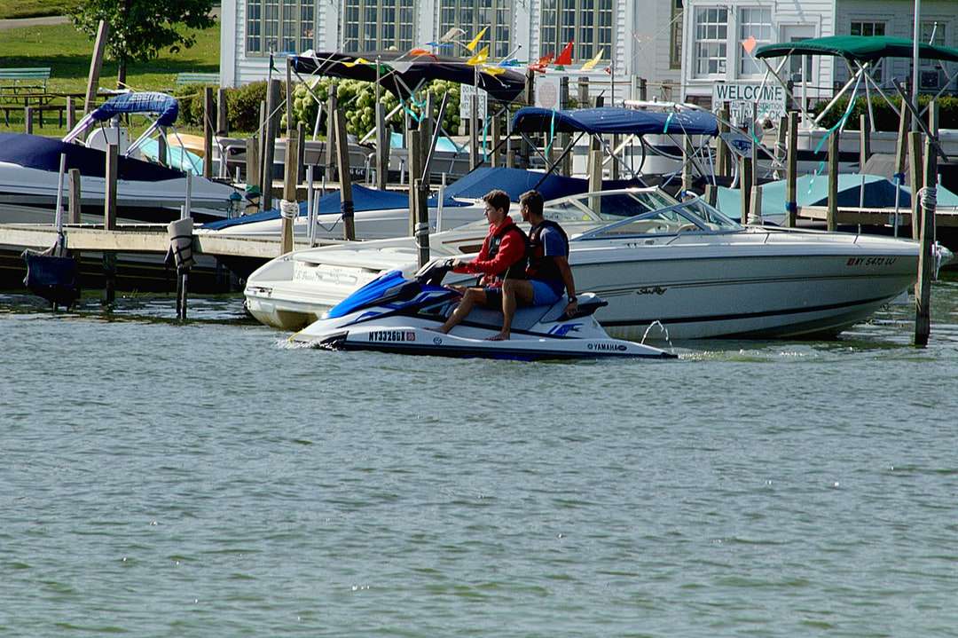Mann im roten Hemd, das auf weißem und blauem Boot reitet Online-Puzzle