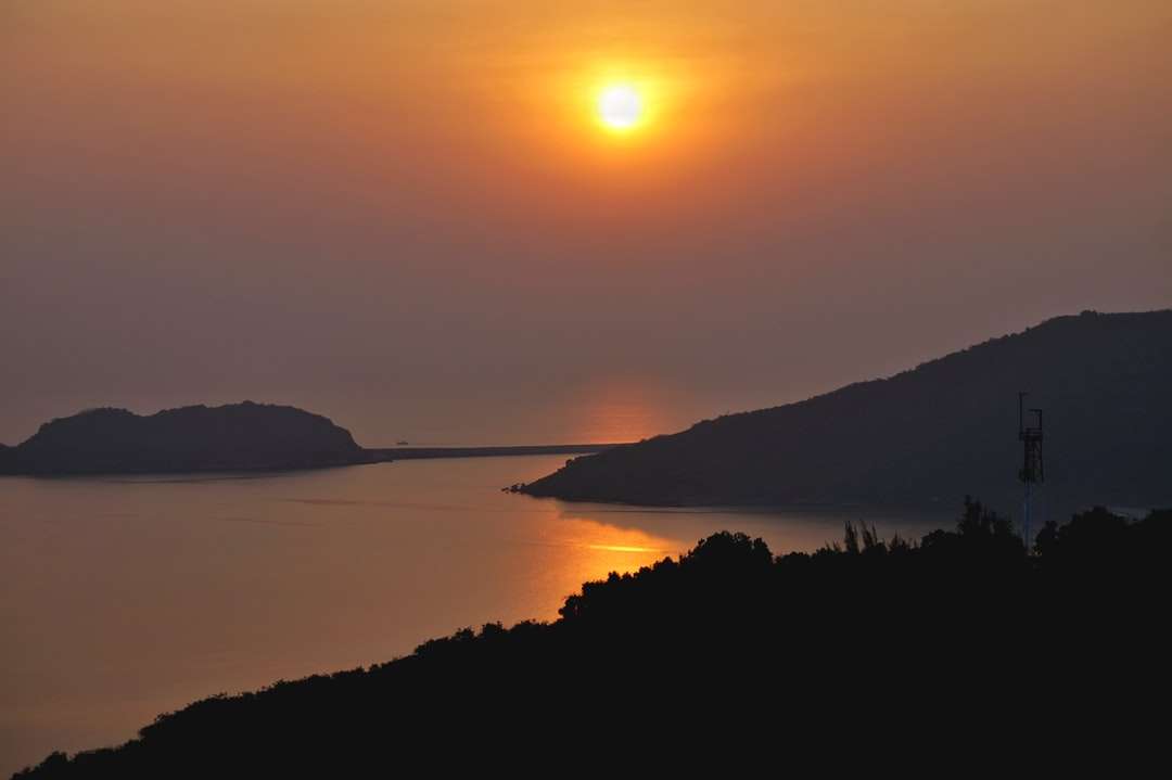 Σιλουέτα του βουνού κοντά στο σώμα του νερού κατά τη διάρκεια του ηλιοβασιλέματος παζλ online