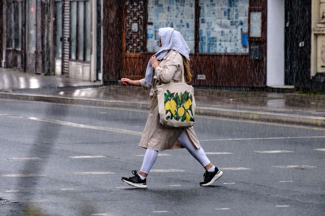 Frau im braunen Mantel, die tagsüber auf dem Bürgersteig läuft Online-Puzzle