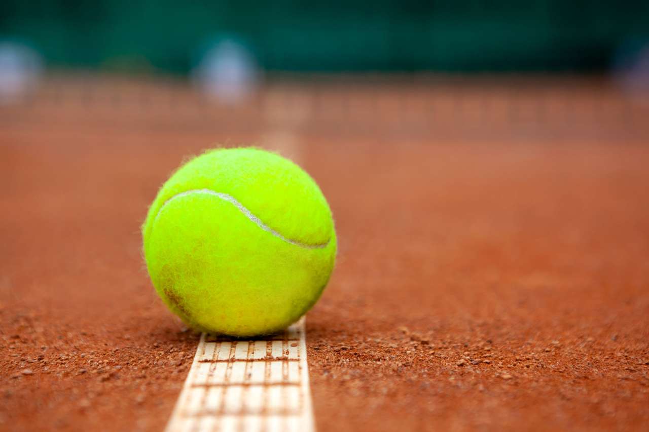 Желтый теннисный мяч на глине пазл онлайн