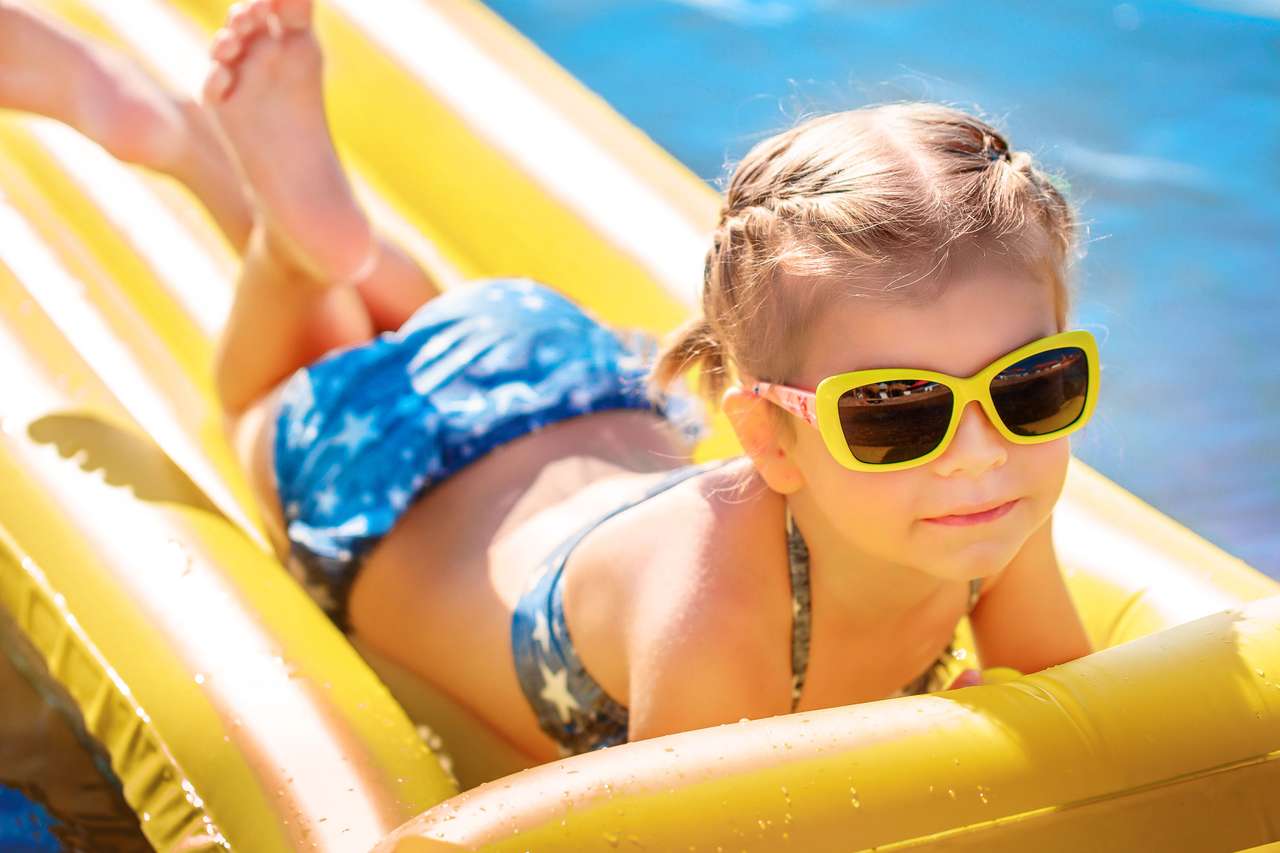 Malá holčička v sluneční brýle plavání na matraci skládačky online