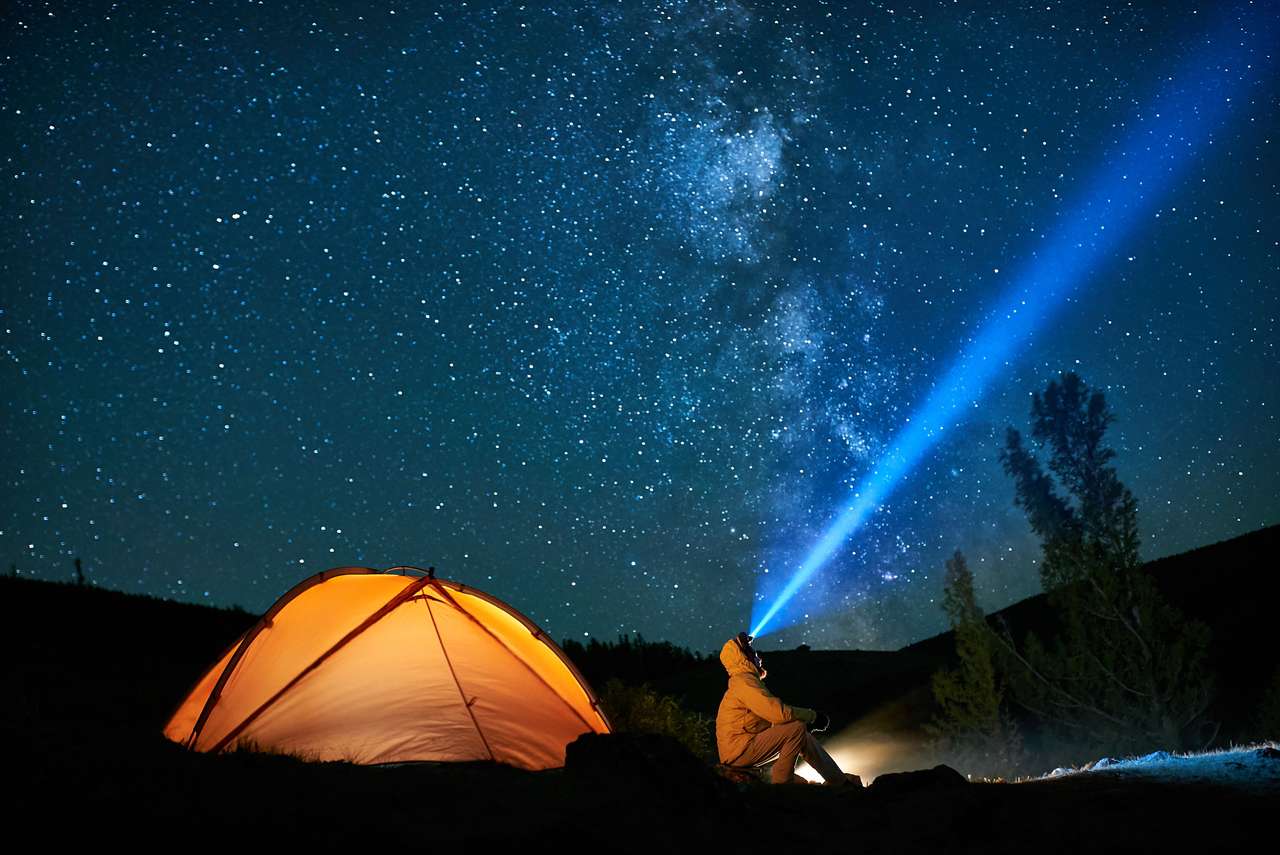 キャンプファイヤーの近くに懐中電灯を持つ観光客の男 ジグソーパズルオンライン