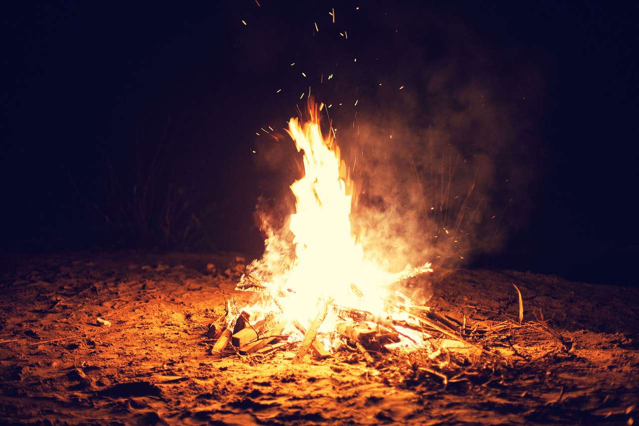 Den ljusa stora brasen brinner på en strand på natten Pussel online