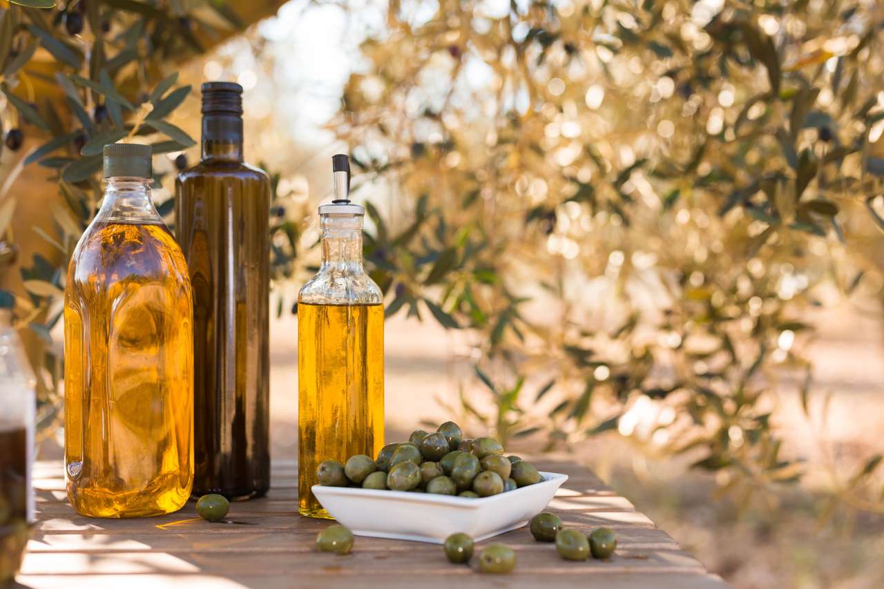 Zelené olivy a olej na stole v olivovém háji online puzzle