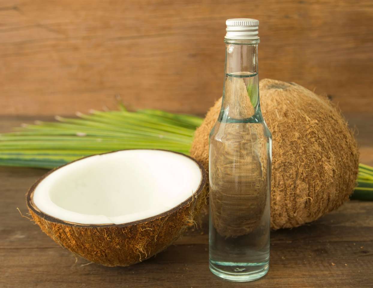 Kokosolja och färska kokosnötter på träbord. Pussel online