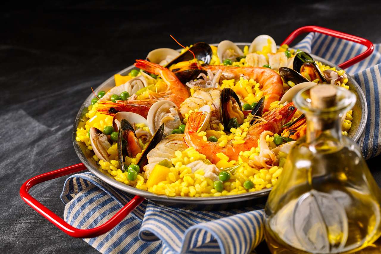 Traditionelles spanisches Rezept für Paella A La Margarita mit rosafarbenen Garnelen, Muscheln und Muscheln auf gelbem Safranreis mit Erbsen, serviert mit Olivenöl für einen leckeren Hakenappetizer Online-Puzzle