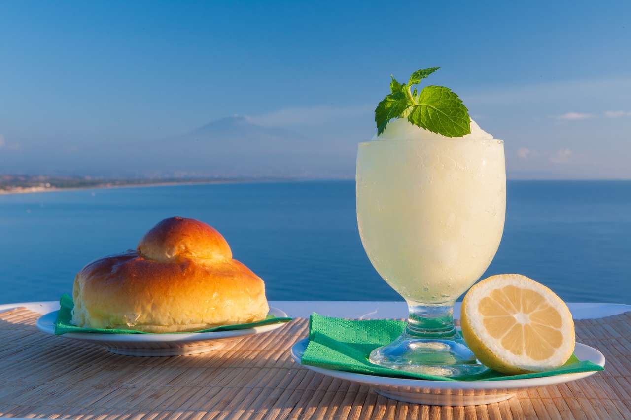 Сицилийская лимонная гранита и типичный теплый бриошь на фоне синего моря и горы этна пазл онлайн