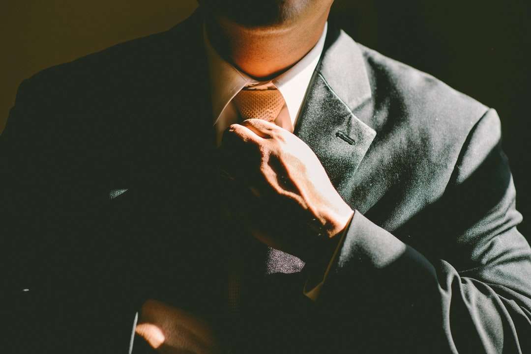 Мъж в черен костюм разхлабва вратовръзката си онлайн пъзел