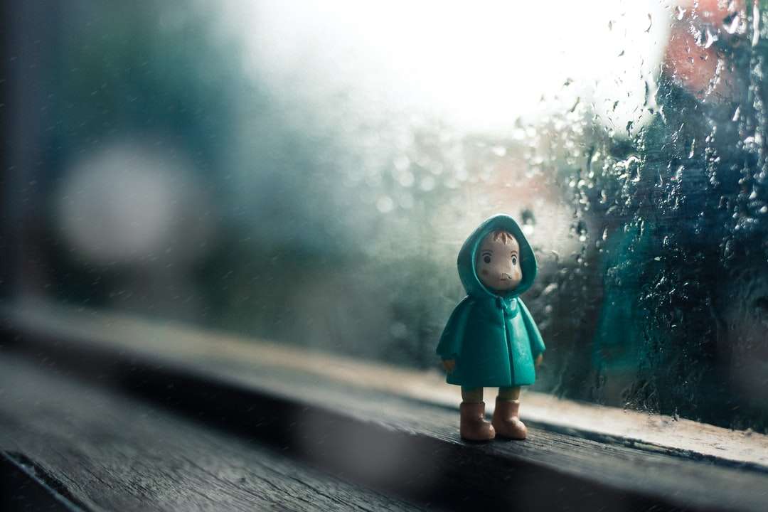 Kind draagt ​​groen jas mini figuur naast glazen venster legpuzzel online