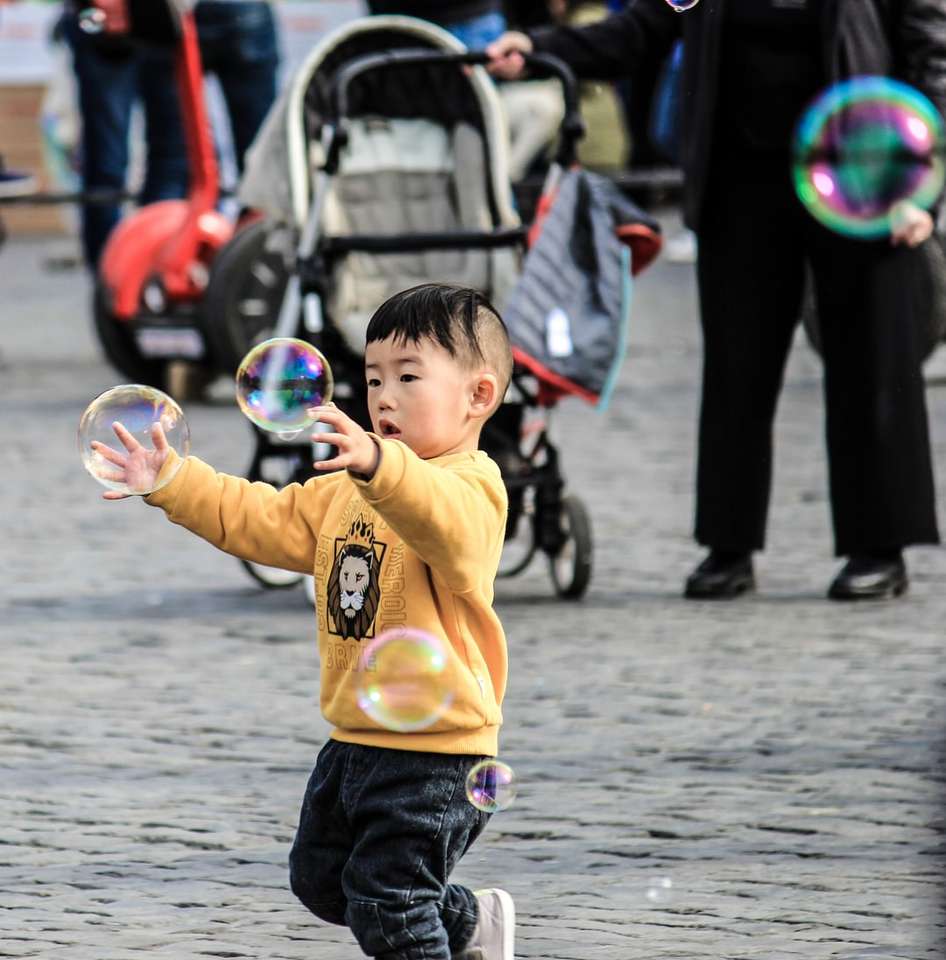 niño con suéter amarillo jugando con burbujas rompecabezas en línea