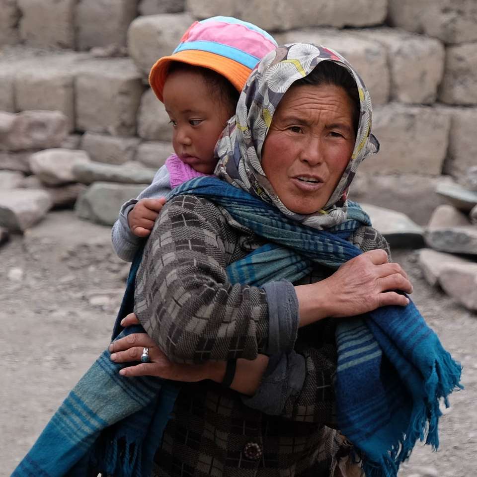 Mujer con bufanda mientras lleva a una niña en su espalda rompecabezas en línea