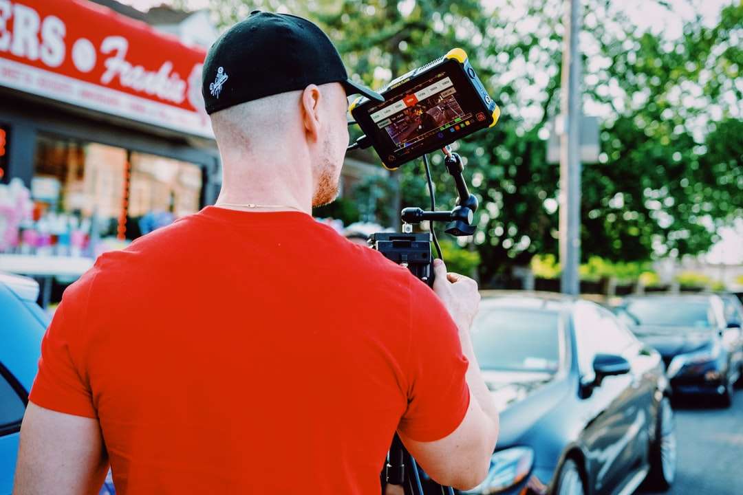 άνδρας με κόκκινη μπλούζα με λαιμόκοψη που κρατά μαύρο smartphone online παζλ
