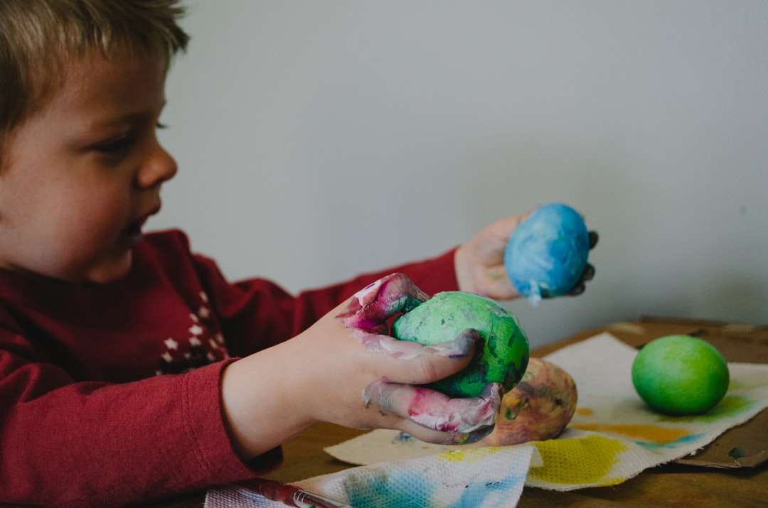 момче, което държи боядисани в синьо и зелено черупки от яйца онлайн пъзел