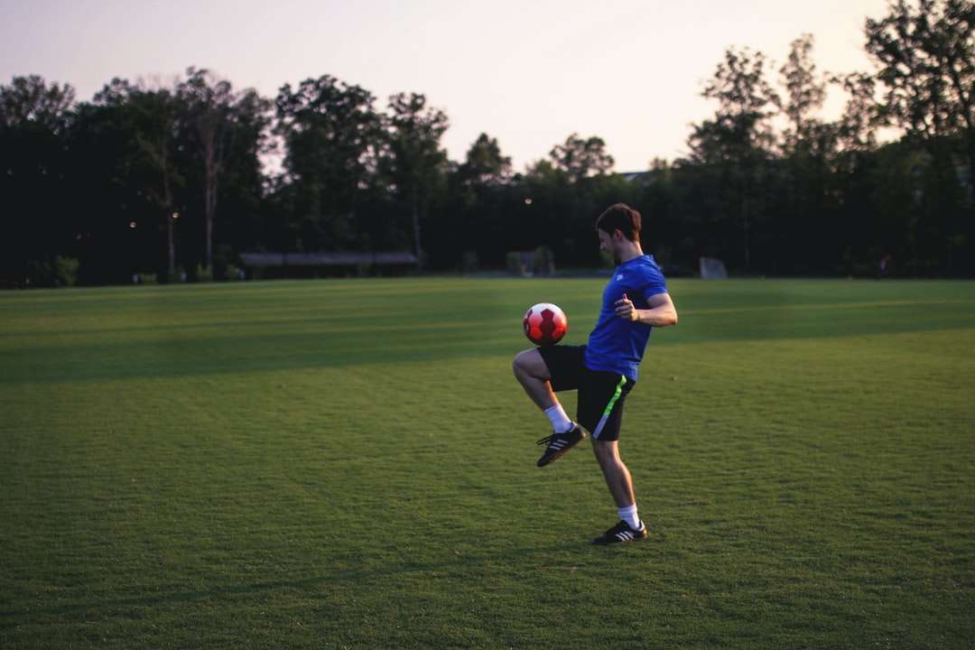 мужчина жонглирует мячом на травяном поле онлайн-пазл