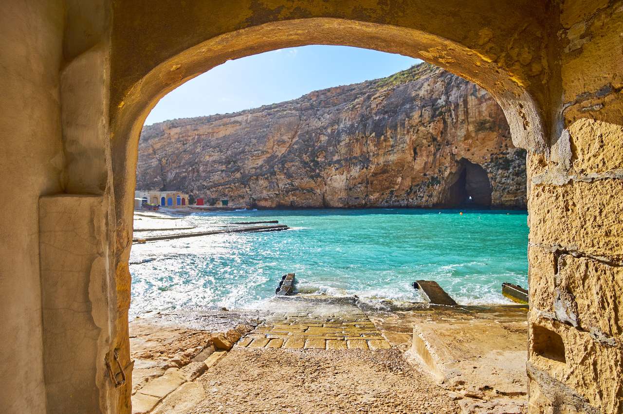 Вид на внутрішнє море Двейра і грот Блакитної діри через арку старого човнового будинку рибальського селища Сан-Лоренц, острів Гозо, Мальта. онлайн пазл
