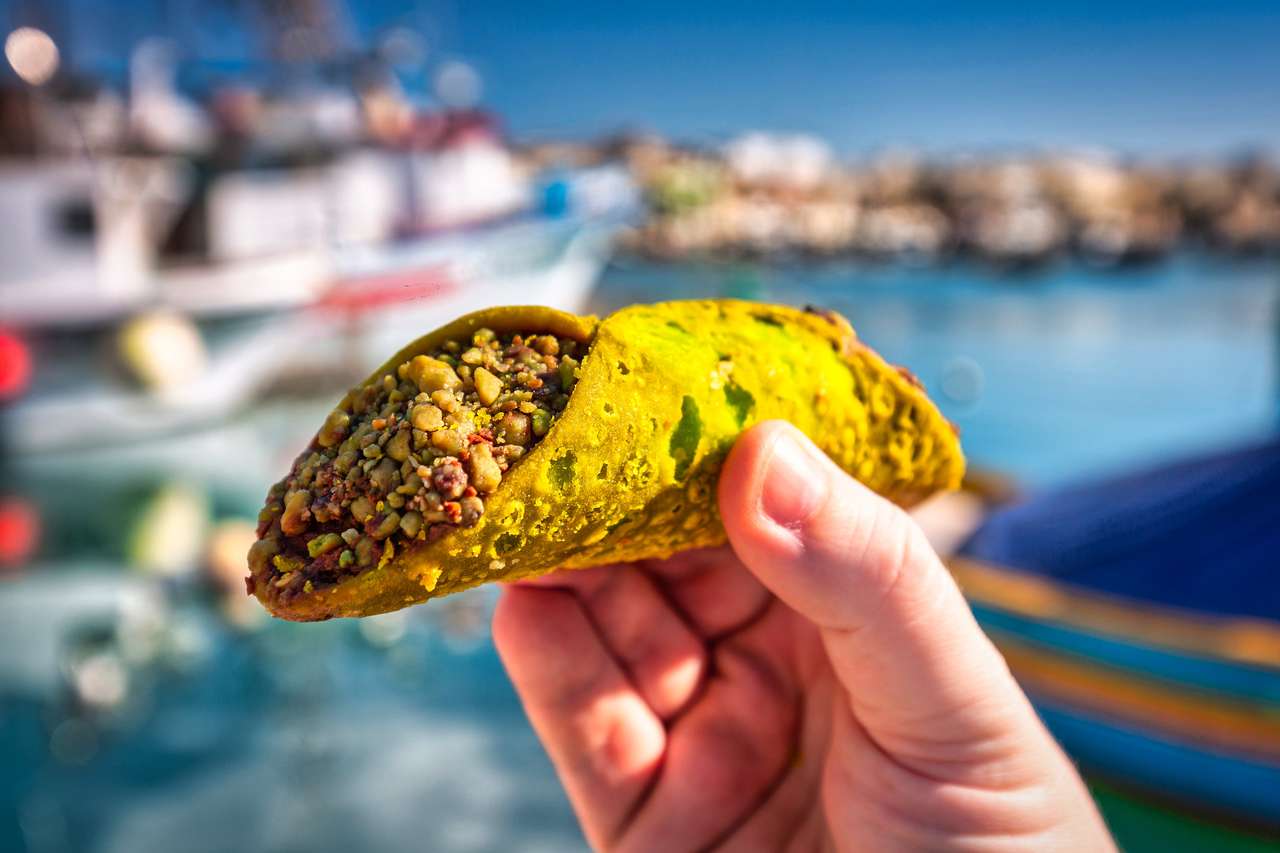 Cannoli de pistache maltês na mão no porto de pesca de Marsaxlokk puzzle online