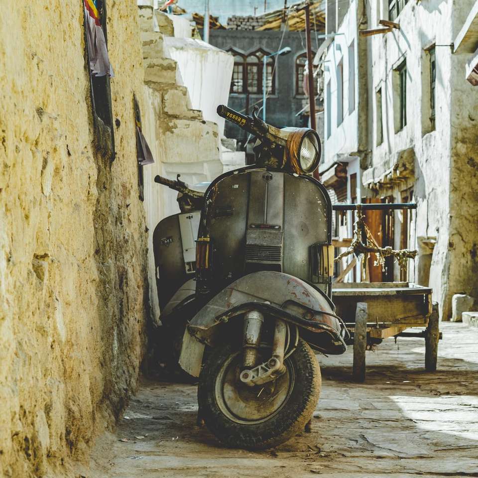 Grijze motor scooter geparkeerd naast bruine muur legpuzzel online
