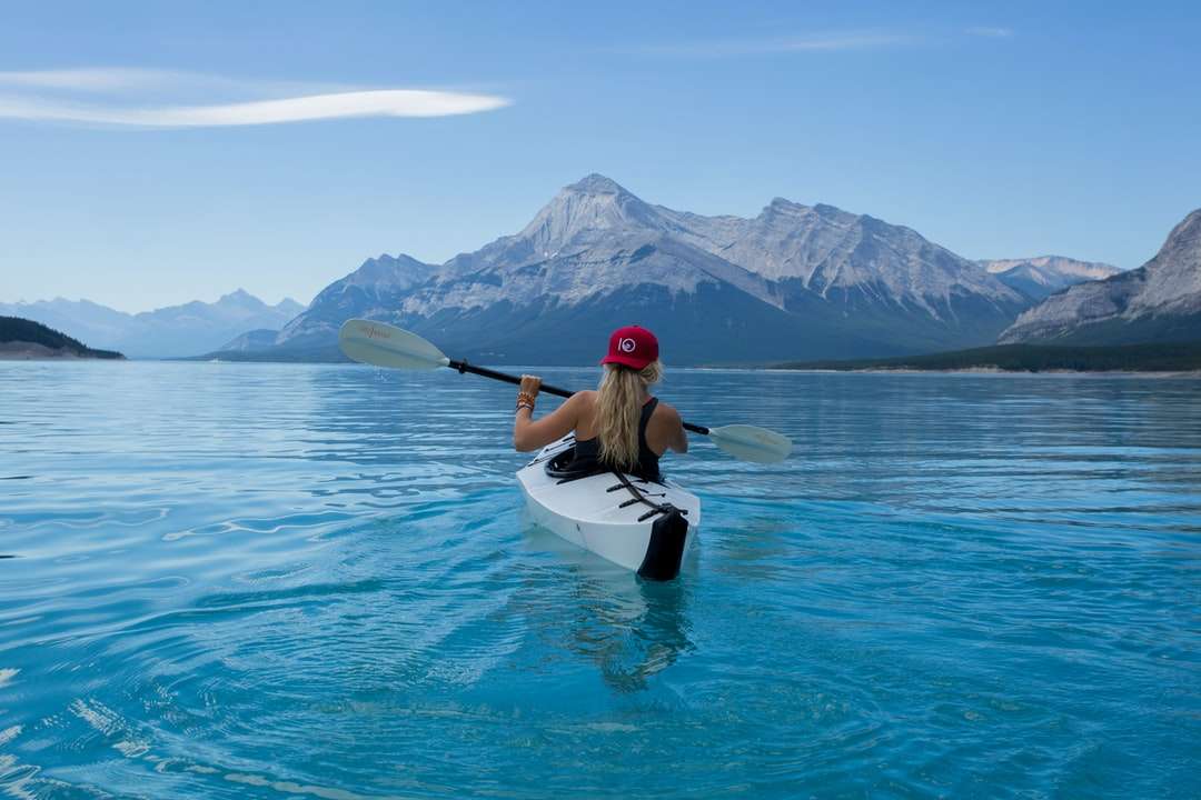 Donna che indossa il cappello rosso che guida sul kayak bianco puzzle online