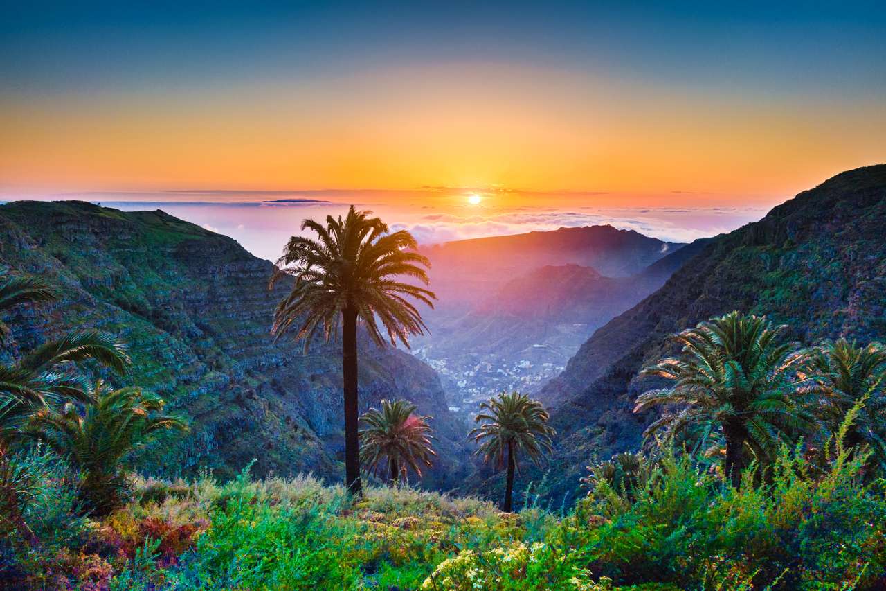 Gyönyörű kilátás csodálatos trópusi tájra egzotikus pálmafák és hegyi völgyek felett széles nyitott tenger arany esti fény napnyugtakor kék ég és felhők nyáron, Kanári-szigetek, Spanyolország kirakós online