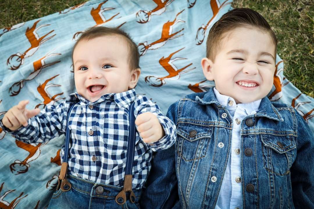 doi băieți întinși pe material textil albastru puzzle online