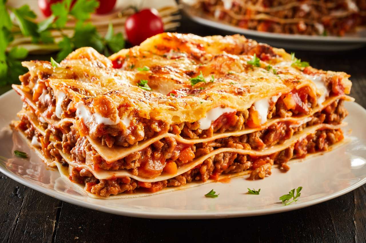 Část šťavnatého mletého hovězího masa lasagne přelité roztavené sýrem a zdobené čerstvou petrželkou podávanou na talíři v zobrazení Zavřít online puzzle