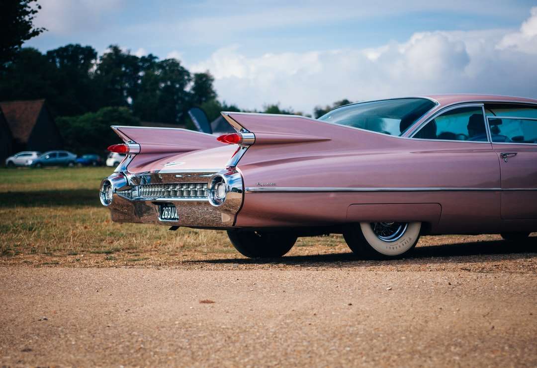 Auto muscolare rosa vintage parcheggiata vicino campo di erba puzzle online
