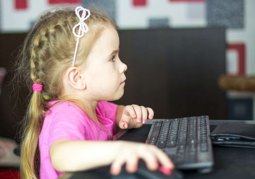 момиче в розова риза, използващо черен лаптоп онлайн пъзел