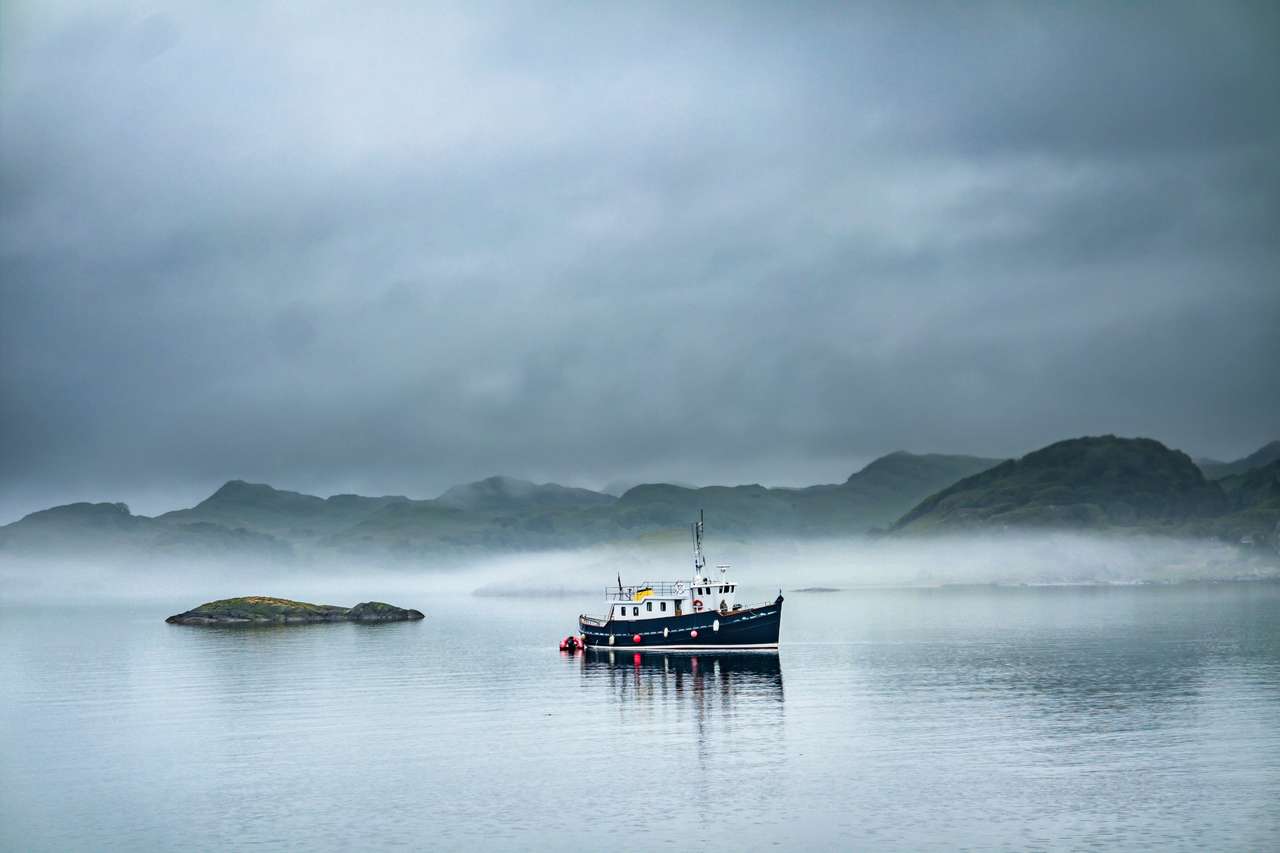 Alone boat driving through in the foggy sea in the scottish highlands online puzzle