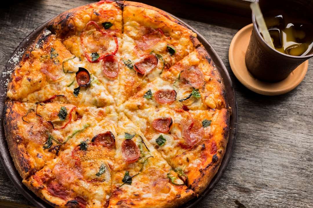 Foto de vista superior da pizza de pepperoni ao lado do copo marrom enchido puzzle online