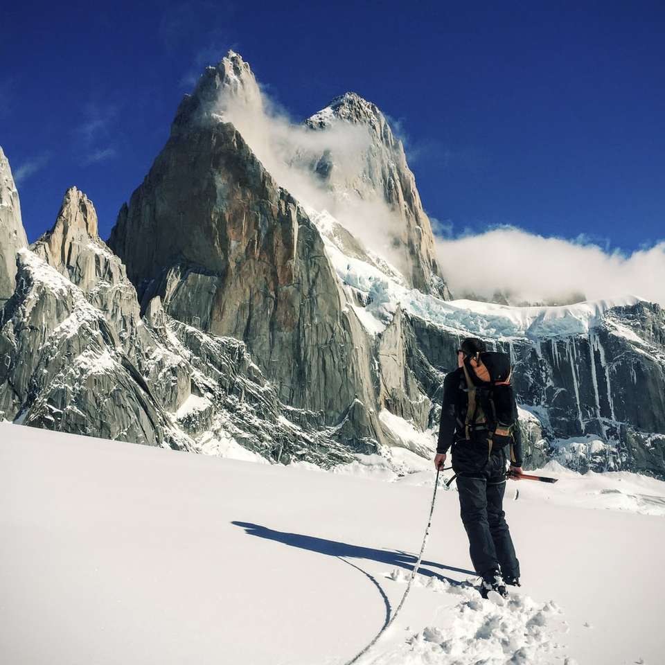 Πρόσωπο με τα πόδια στο χιόνι πεδίο κοντά στο βουνό παζλ online