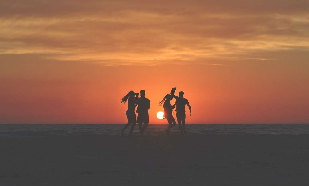 Silhuettfoto av fyra personer dansar på sand Pussel online