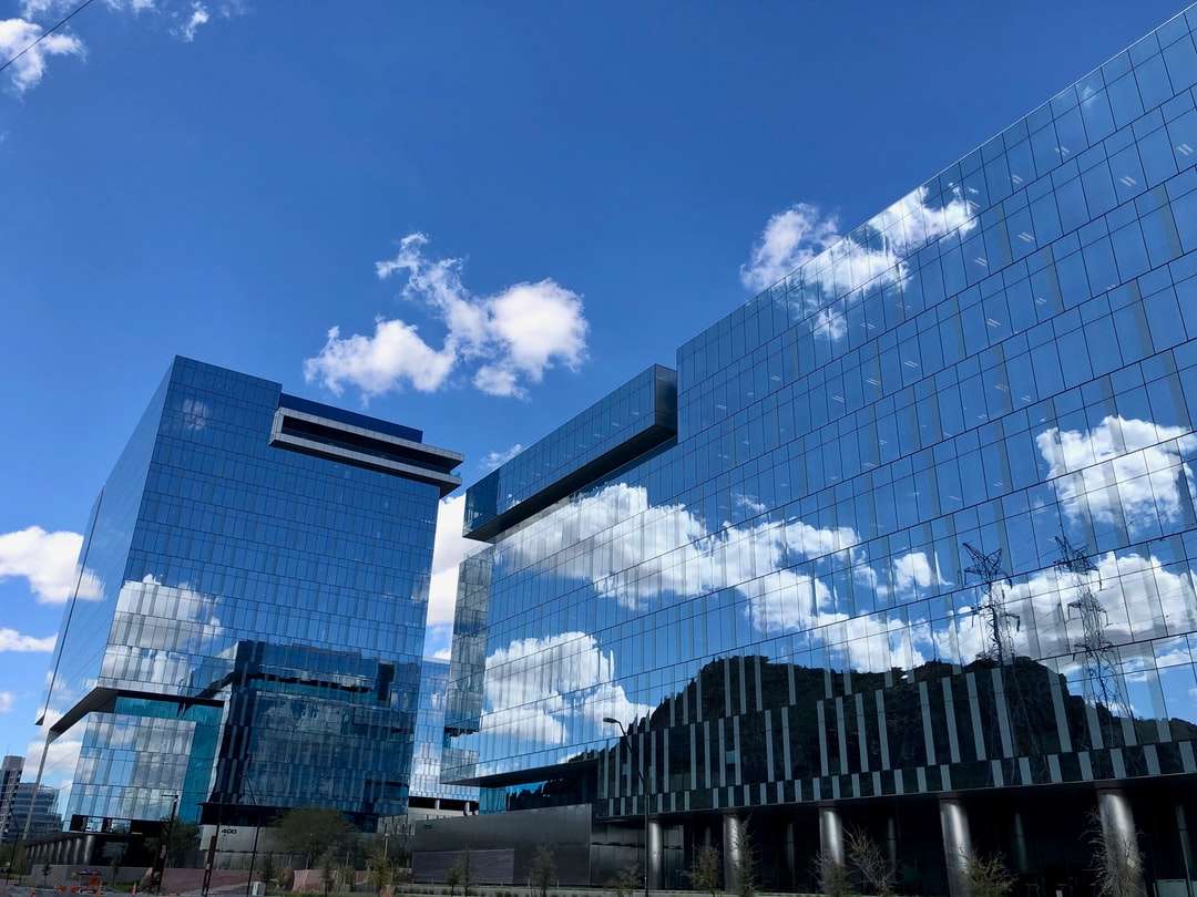 Edificio de cristal azul y blanco bajo el cielo azul durante el día. rompecabezas en línea