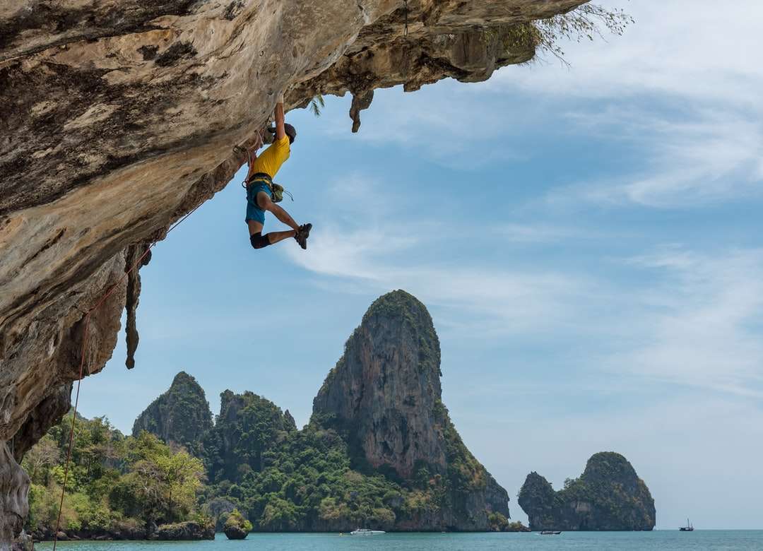 Hombre escalando acantilado al lado de la playa rompecabezas en línea
