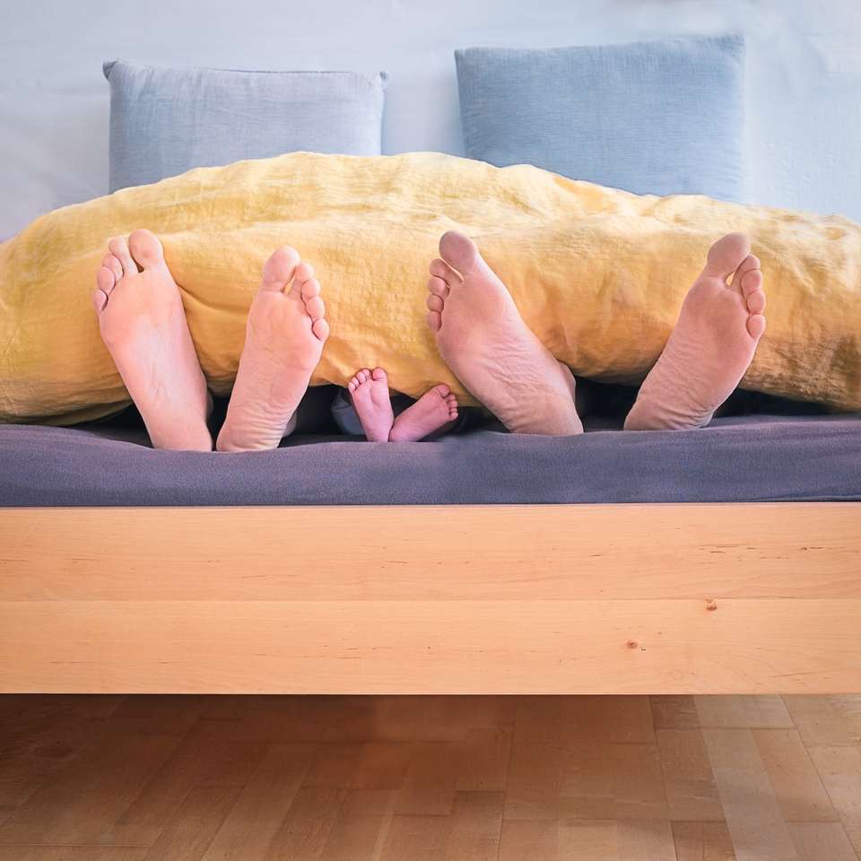 três pessoas debaixo de cobertor de cama amarelo quebra-cabeças online