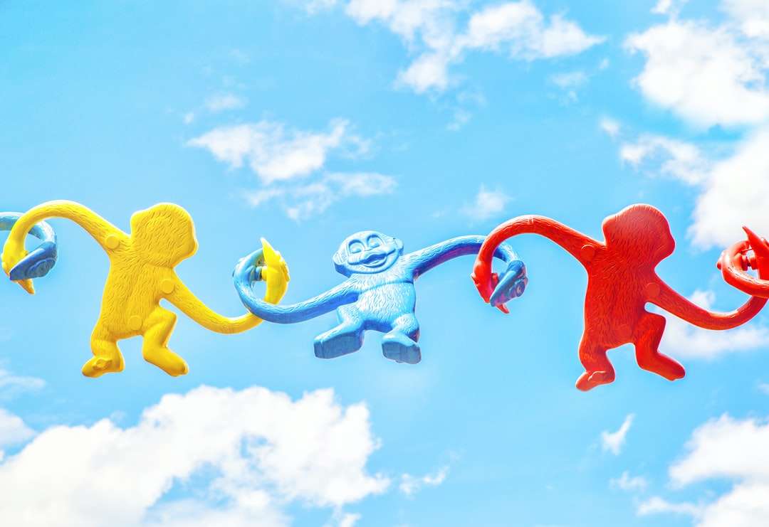 Tři nejrůznější-barevné opice plastové hračky drží navzájem skládačky online