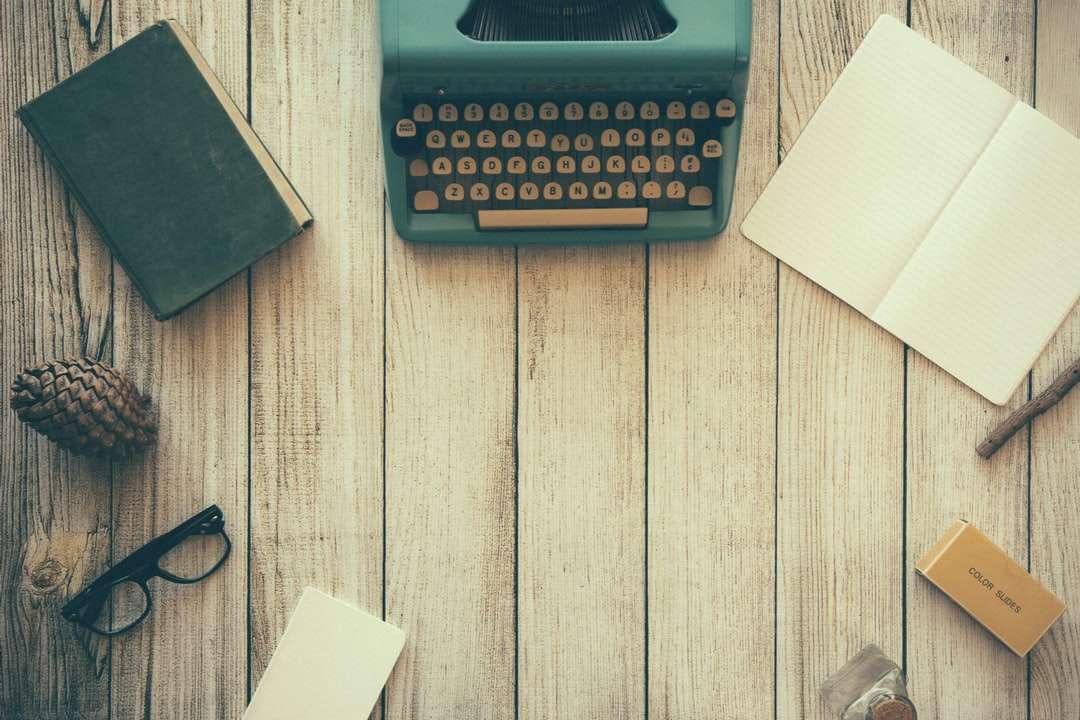 Vintage blaugrüne Schreibmaschine neben Buch Online-Puzzle