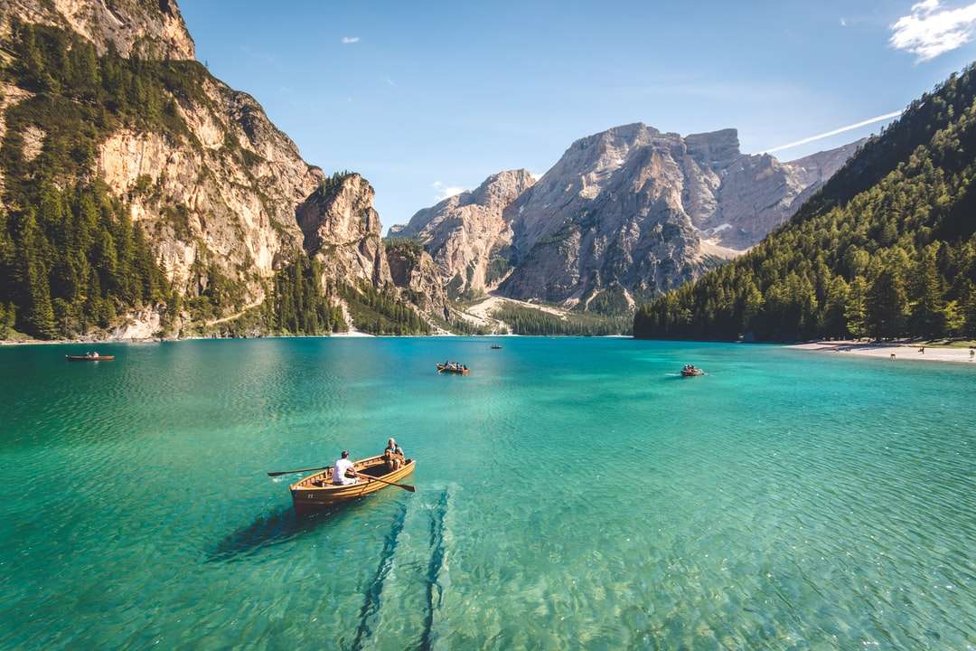 Három barna fából készült csónak a kék tó vízben, amelyet napközben vettek kirakós online