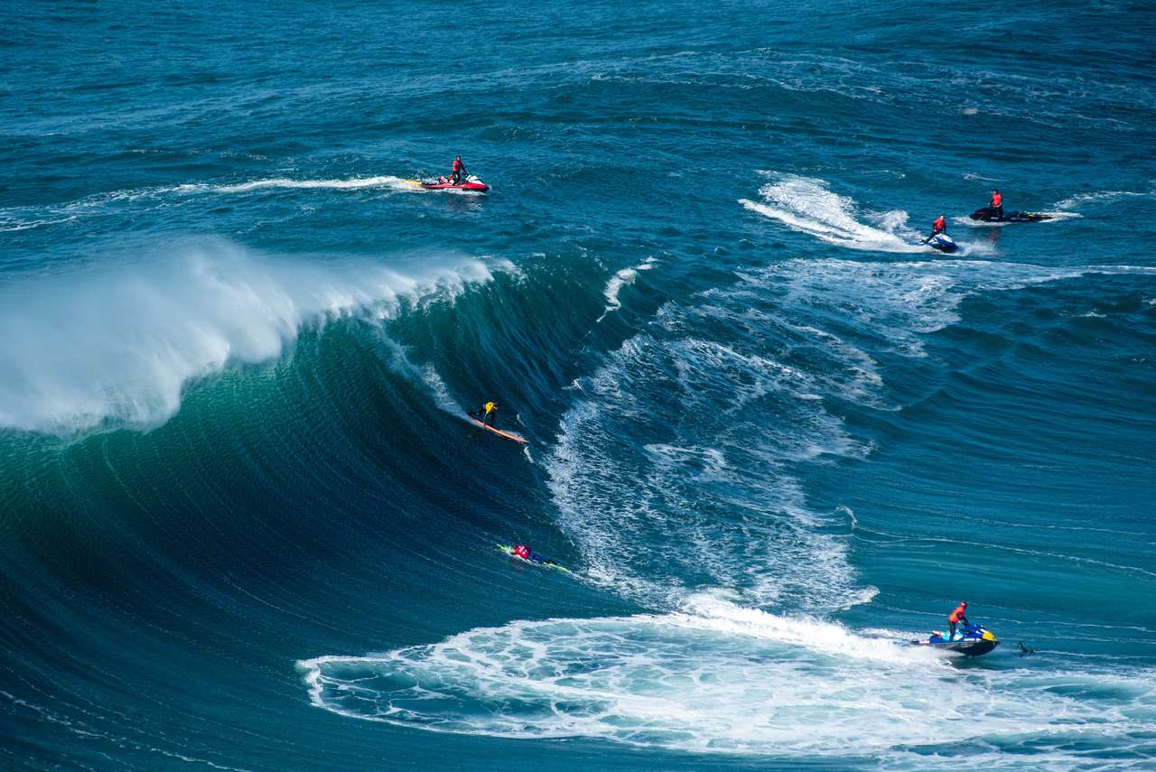 Οι Surfers που ταξιδεύουν στον Ατλαντικό Ωκεανό κοντά στον δήμο Nazare στην Πορτογαλία παζλ online
