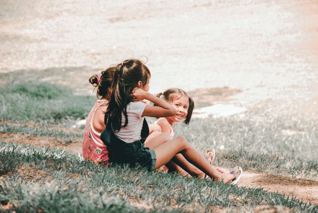 Tre barn sitter på gräs Pussel online