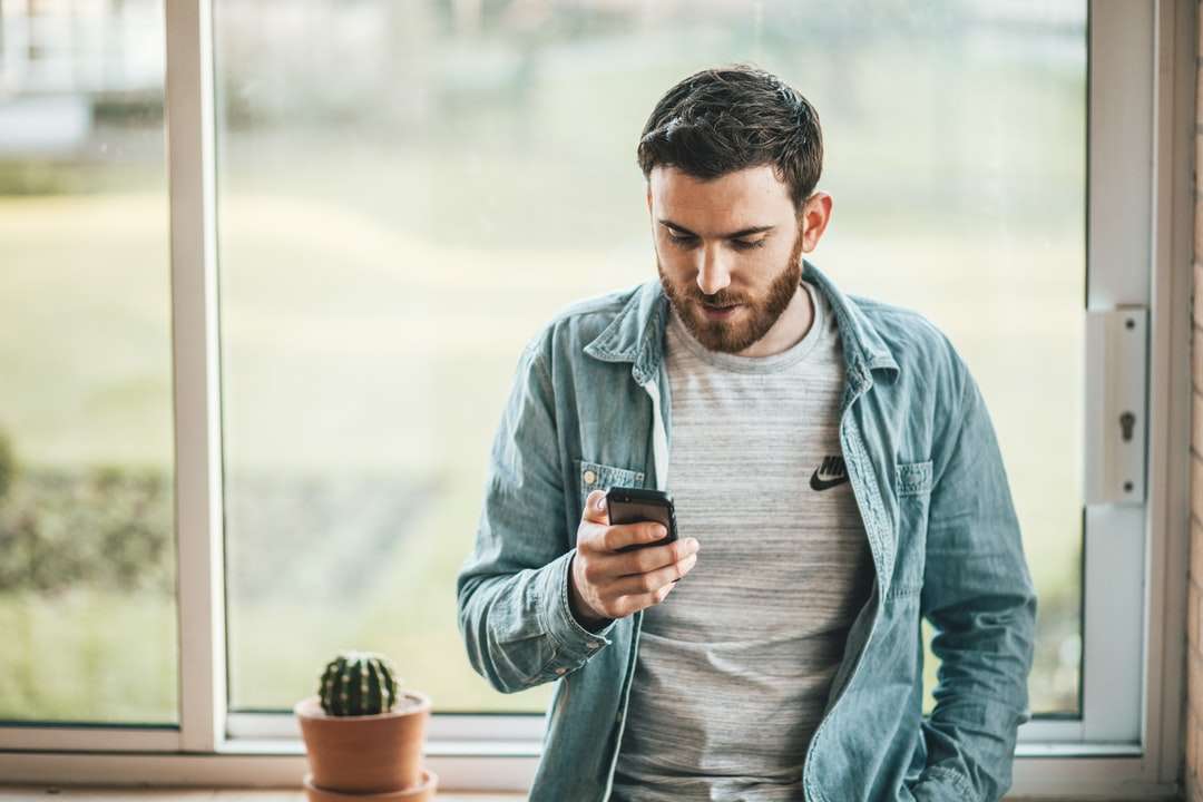 man met een smartphone bij het raam legpuzzel online